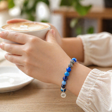 Load image into Gallery viewer, Person wearing MysticFlavia Blue Striped Agate bracelet while holding a coffee cup

