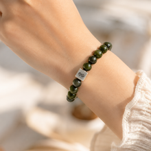Load image into Gallery viewer, Person wearing MysticFlavia Jade infinity bracelet with silver charm on wrist

