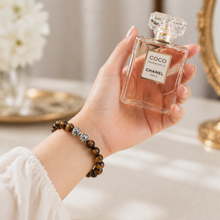 Load image into Gallery viewer, Woman wearing MysticFlavia tiger eye bracelet on wrist, elegant lifestyle shot with perfume bottle
