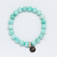 Amazonite flat silver bead bracelet with soft teal-green round beads and dark round silver brand charm pendant, white background
