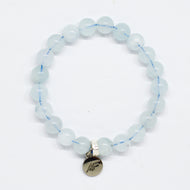 Aquamarine Birthstone flat silver bracelet with pale blue translucent beads and round silver brand charm pendant, white background
