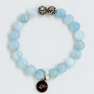 Aquamarine Birthstone round silver bracelet with pale blue beads, two carved silver beads on top and dark round brand charm pendant, white background
