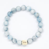 Aquamarine Birthstone bracelet with pale blue round beads, two carved silver beads on top and square infinity charm, white background
