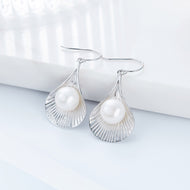 Silver pearl dangle earrings with round white pearls on a white background.