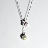Star pendant lariat necklace in silver with dangling pearl drop, front view on white background.
