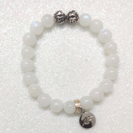 MysticFlavia moonstone bracelet with white beads, two carved silver beads on top and dark round brand charm pendant, white background
