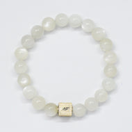 MysticFlavia moonstone bracelet with milky white round beads and square silver brand tag, white background
