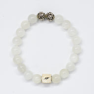 MysticFlavia moonstone bracelet with translucent white beads, two carved silver beads on top and square brand tag, white background

