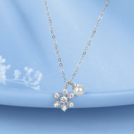 Silver pearl pendant necklace with floral crystal design on blue background