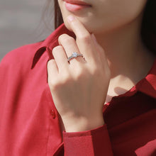 Load image into Gallery viewer, Woman wearing a round moissanite silver ring with delicate side stones
