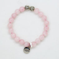 Rose quartz bracelet with silver charm and decorative beads on white background