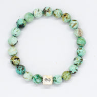 Turquoise infinity silver bracelet with natural green-brown speckled beads and square infinity charm at bottom, white background
