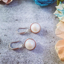 Load image into Gallery viewer, White pearl silver drop earrings styled on a model’s ear.
